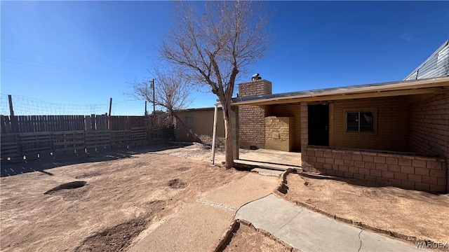 exterior space featuring a chimney, fence, and a patio