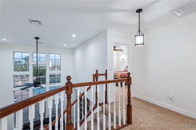 corridor with baseboards, visible vents, carpet flooring, and an upstairs landing