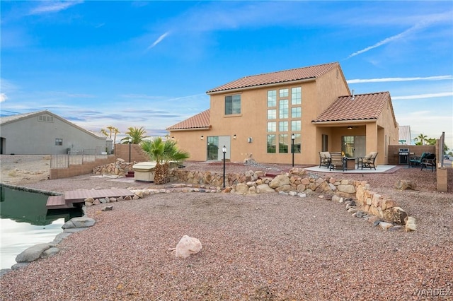 back of property with stucco siding, a patio, a tiled roof, and fence