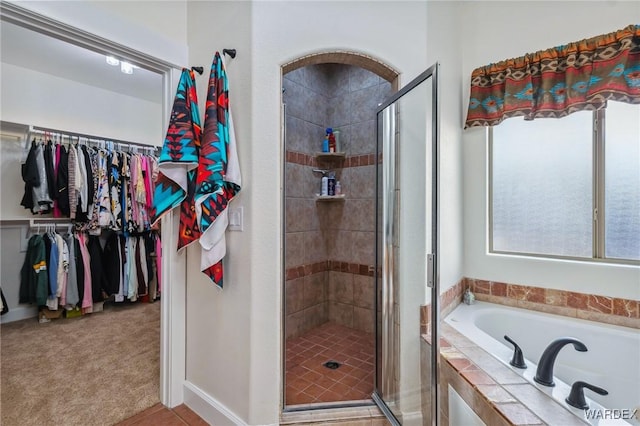 bathroom featuring a garden tub, a stall shower, and a walk in closet