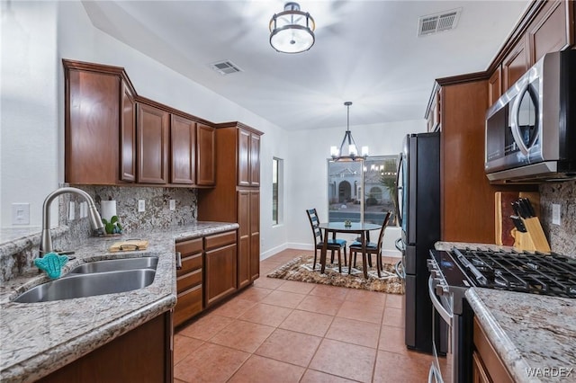 kitchen featuring appliances with stainless steel finishes, visible vents, a sink, and light stone countertops