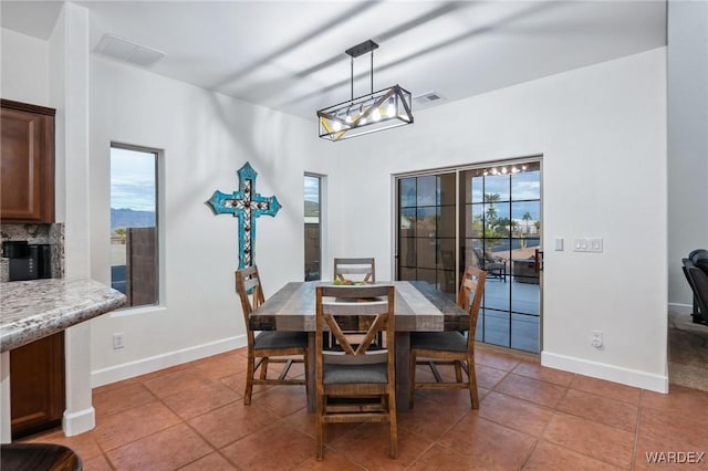 tiled dining space featuring a notable chandelier, visible vents, and baseboards