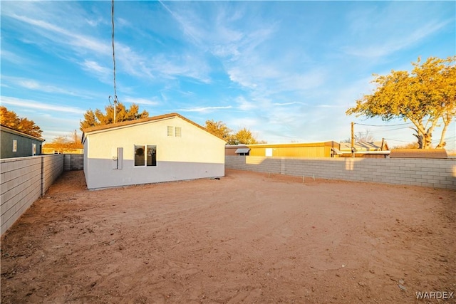 back of house with a fenced backyard and stucco siding