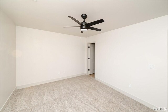 spare room with baseboards, ceiling fan, and light colored carpet