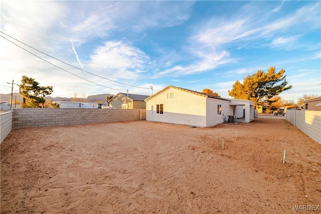 rear view of property with cooling unit, a fenced backyard, and stucco siding