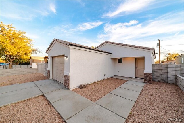 exterior space with a garage, driveway, fence, and stucco siding