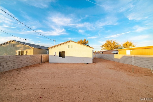 rear view of house featuring a fenced backyard and stucco siding