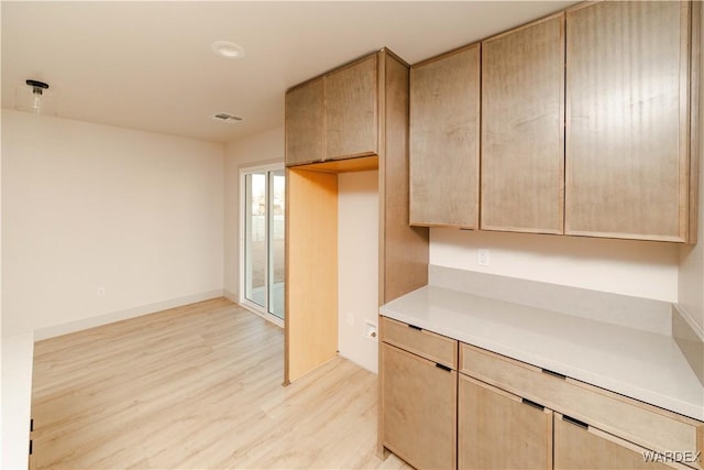 kitchen with light countertops, light brown cabinetry, and visible vents