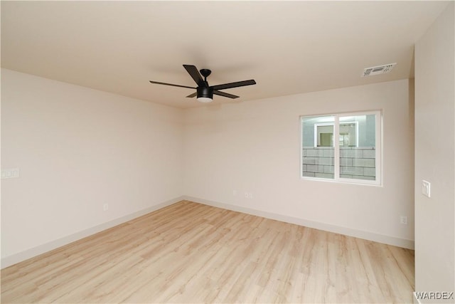 spare room with light wood-type flooring, baseboards, visible vents, and a ceiling fan