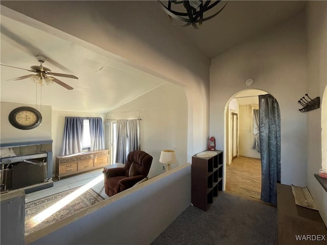 carpeted living area featuring vaulted ceiling, arched walkways, and a ceiling fan