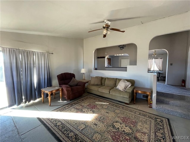 living area with a ceiling fan and arched walkways