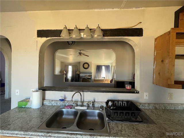 kitchen featuring ceiling fan, arched walkways, and a sink