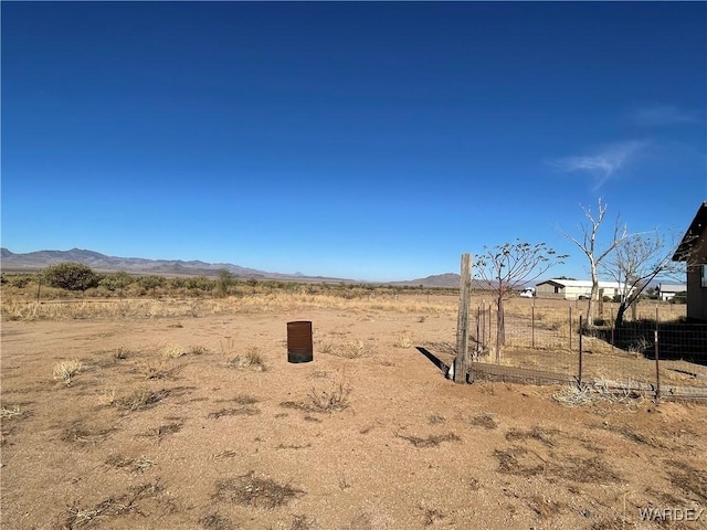 view of yard with fence, a mountain view, and a rural view