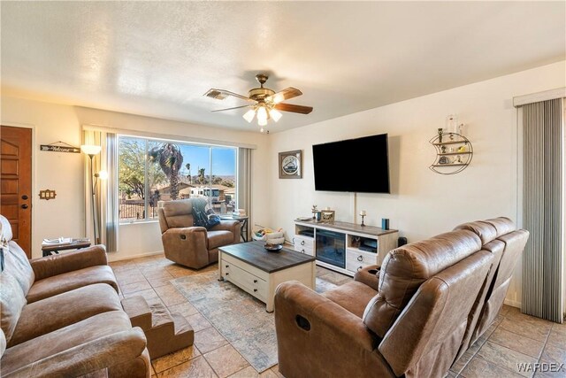 living area with a ceiling fan, visible vents, and baseboards