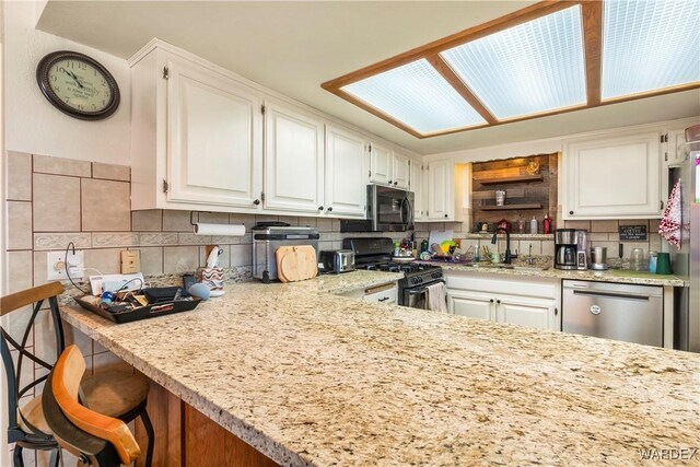 kitchen featuring white cabinetry, black gas stove, a sink, and stainless steel dishwasher