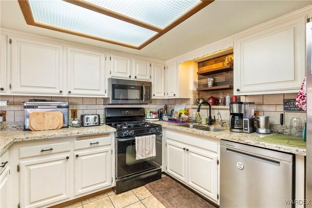 kitchen featuring stainless steel appliances, white cabinets, a sink, and backsplash