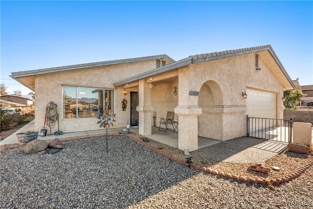 view of front facade with a garage, a patio, and stucco siding