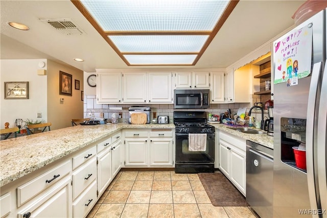 kitchen with a sink, visible vents, white cabinets, appliances with stainless steel finishes, and decorative backsplash