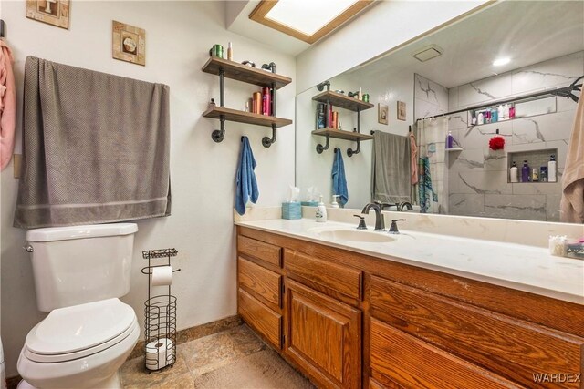 bathroom featuring a skylight, toilet, vanity, a shower with curtain, and baseboards