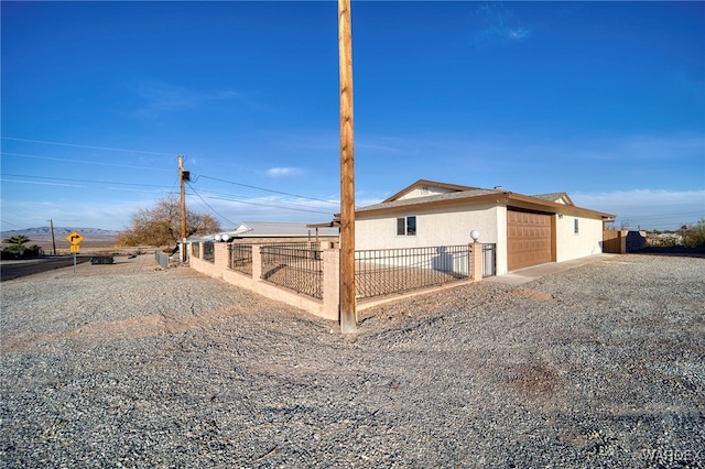 exterior space featuring an attached garage, fence, and gravel driveway