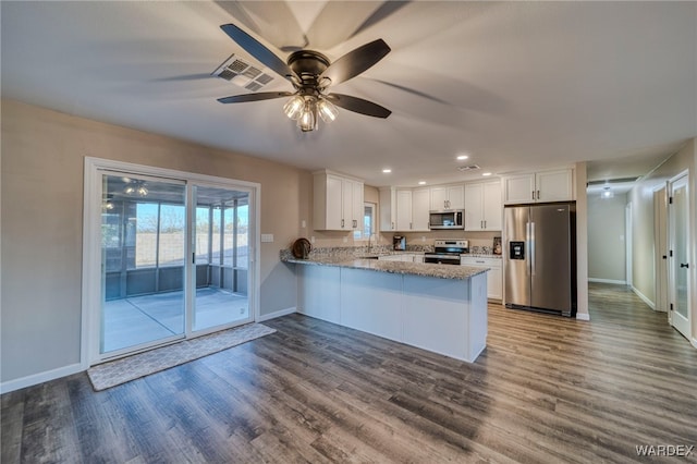 kitchen with stainless steel appliances, visible vents, white cabinetry, wood finished floors, and a peninsula