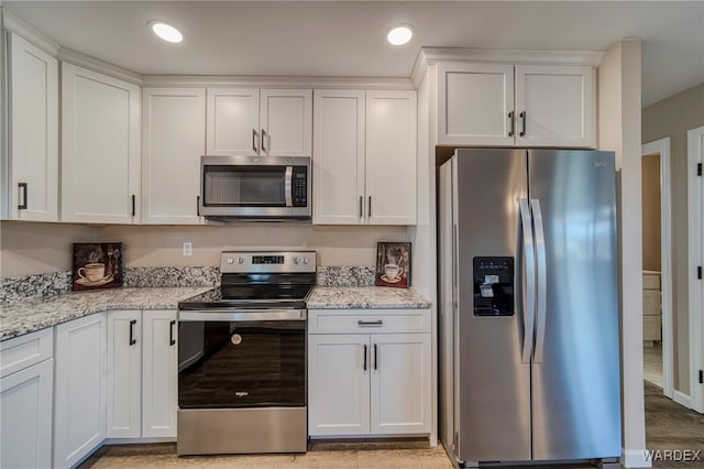 kitchen with white cabinets, light stone countertops, stainless steel appliances, and recessed lighting