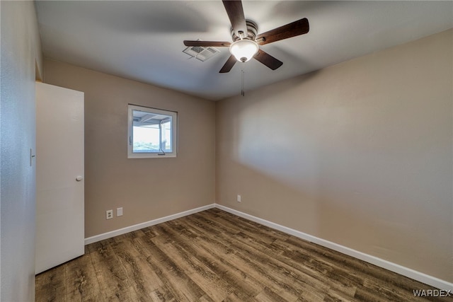 empty room featuring dark wood-type flooring, visible vents, ceiling fan, and baseboards