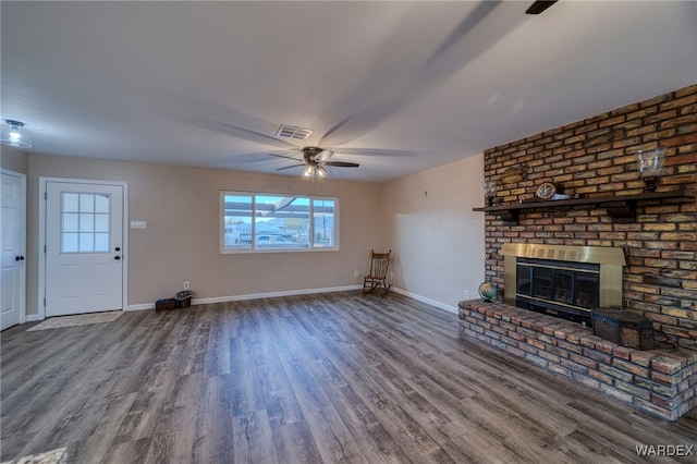 unfurnished living room with a brick fireplace, ceiling fan, baseboards, and wood finished floors