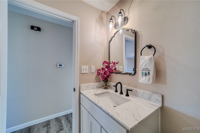 bathroom featuring wood finished floors, vanity, and baseboards