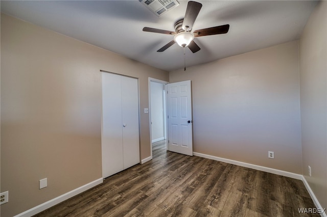 unfurnished bedroom with dark wood-type flooring, a closet, visible vents, and baseboards