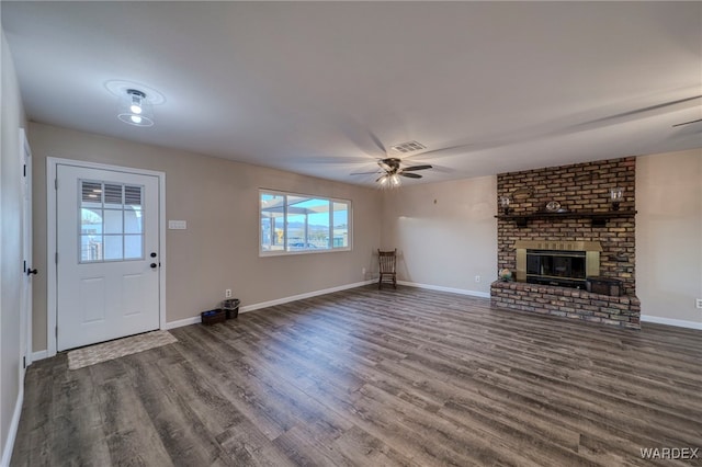 unfurnished living room with visible vents, baseboards, a ceiling fan, dark wood-type flooring, and a brick fireplace