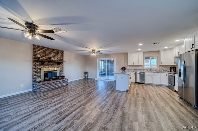 kitchen with stainless steel appliances, visible vents, white cabinetry, open floor plan, and light wood-type flooring