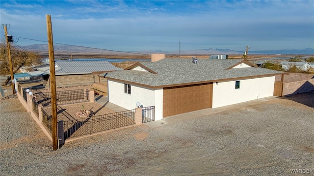 view of front of property featuring driveway, roof with shingles, fence, a mountain view, and stucco siding