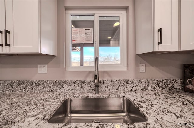 details featuring light stone countertops, white cabinetry, and a sink