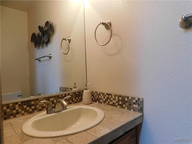 bathroom with tasteful backsplash, vanity, and toilet