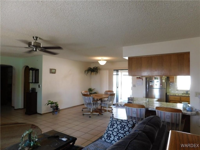 living room with arched walkways, ceiling fan, a textured ceiling, and light tile patterned flooring