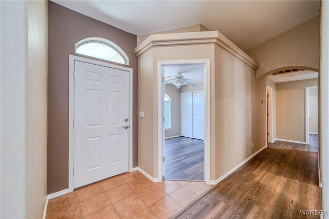 entryway with arched walkways, lofted ceiling, wood finished floors, visible vents, and baseboards