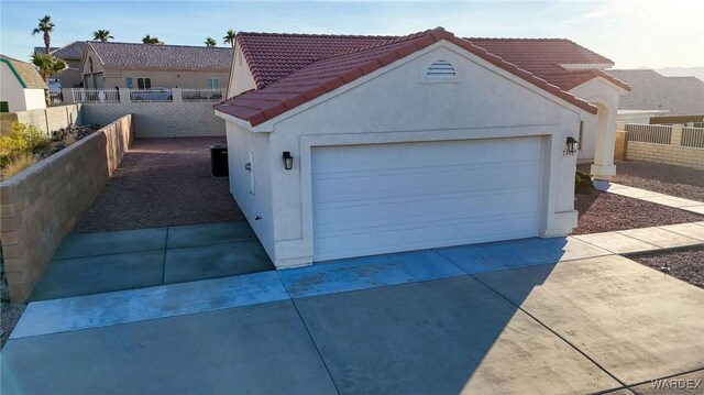 garage with concrete driveway and fence