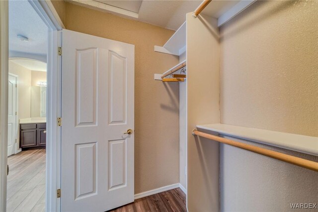 spacious closet with arched walkways and light wood finished floors