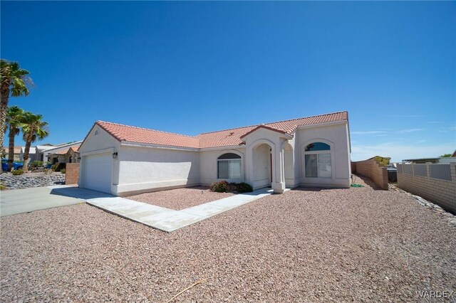 mediterranean / spanish-style house with a garage, a tiled roof, driveway, and stucco siding