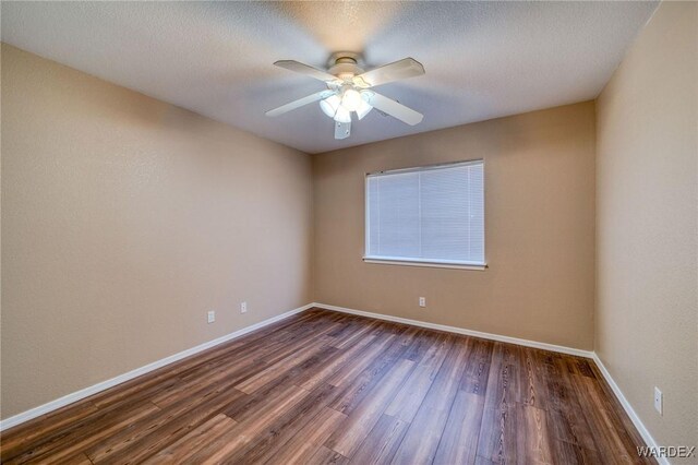 empty room with a textured ceiling, baseboards, dark wood finished floors, and a ceiling fan