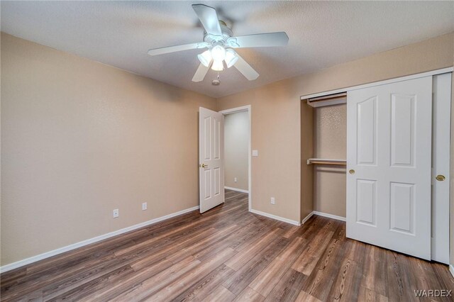 unfurnished bedroom featuring dark wood-type flooring, a closet, a ceiling fan, and baseboards