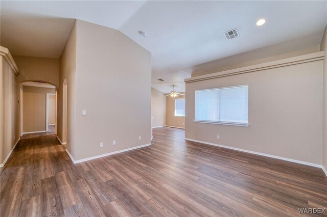 unfurnished room with arched walkways, lofted ceiling, a ceiling fan, wood finished floors, and baseboards