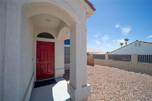 doorway to property featuring fence and stucco siding