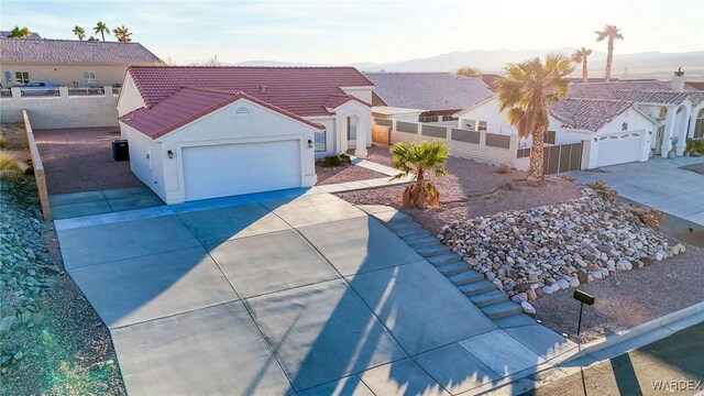 view of front facade with a tiled roof, a residential view, fence private yard, and driveway