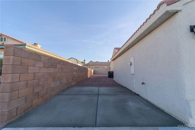 view of home's exterior featuring a tile roof, central air condition unit, stucco siding, a patio area, and fence