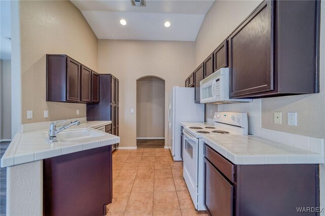 kitchen featuring dark brown cabinets, white appliances, and tile counters