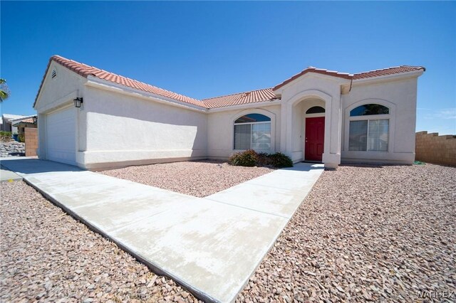 mediterranean / spanish-style home with a tile roof, an attached garage, and stucco siding