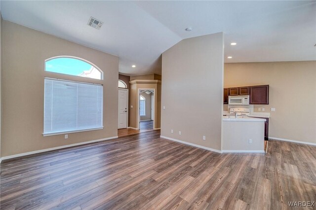 interior space with lofted ceiling, dark wood-style flooring, visible vents, and baseboards