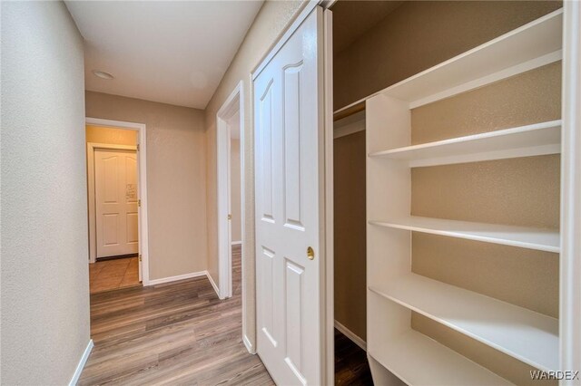 corridor featuring baseboards and wood finished floors